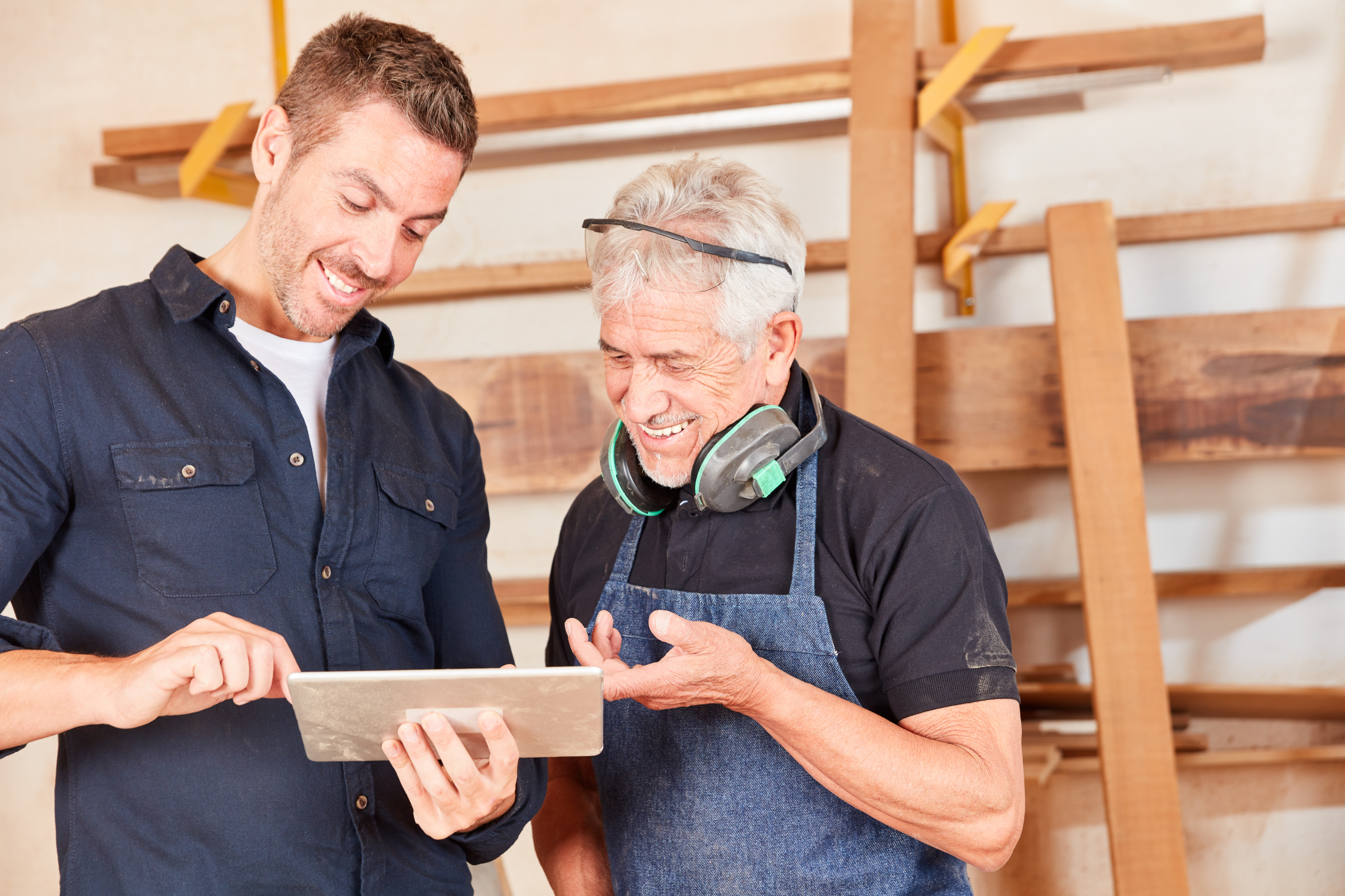 Young carpenter and master craftsman with tablet