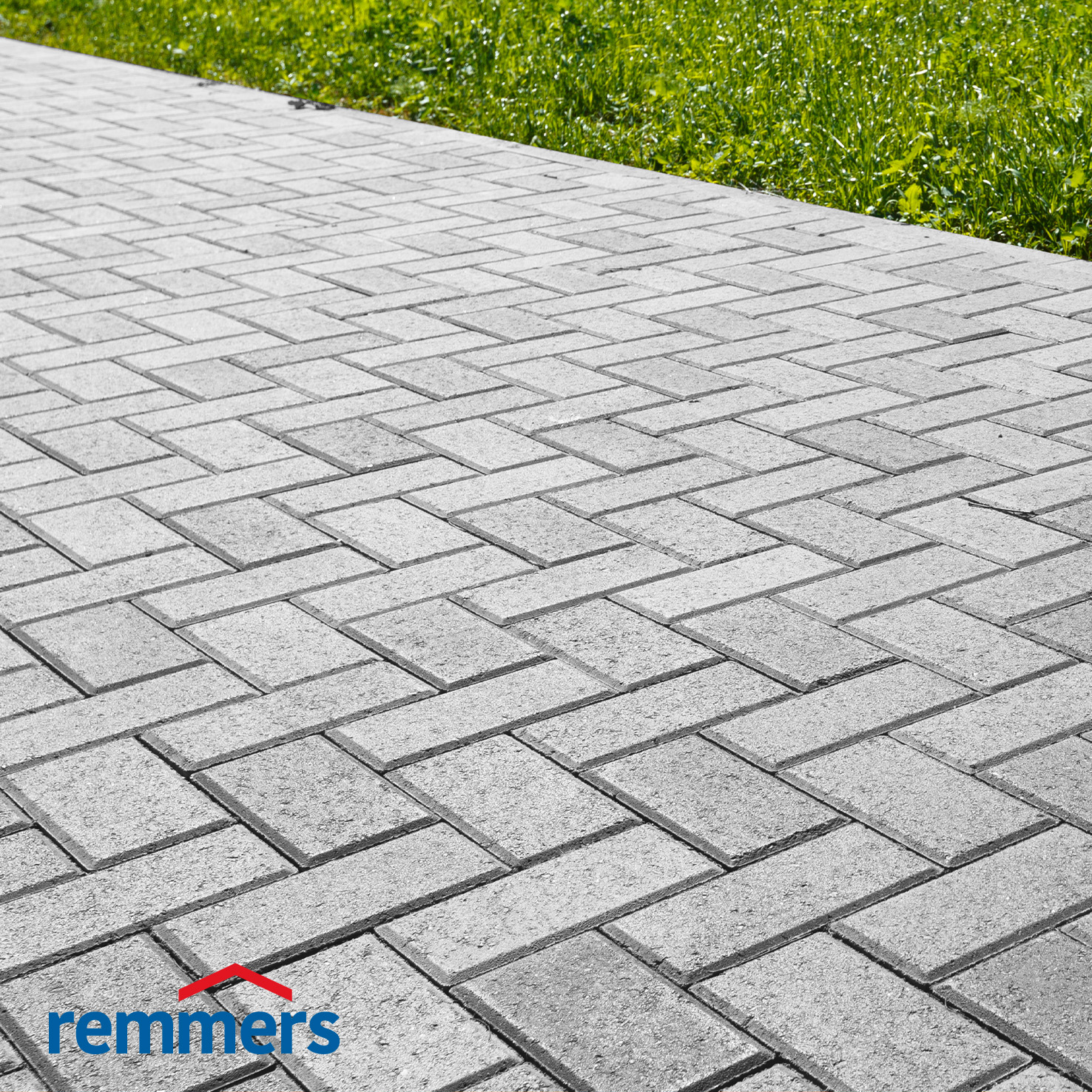 Kopfsteinpflaster und Rasen, getrennt durch einen Betonrandstein.